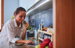 © lenets_tan - Young woman using tablet in kitchen at home and drinking coffee