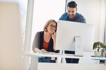 Fototapete - Teamwork and unity of two colleagues and coworkers working together on a computer in the office. Business man and woman talking, discussing and planning in a meeting for brainstorming ideas at work