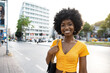 © fotofabrika - Portrait of a young african american woman smiling standing at the city.