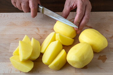 Wall Mural - Hands with knife cutting potatoes, preparing potatoes for cooking.