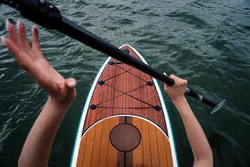 Sports girl on board for glanders surfing. A young slender woman floats on a board with a paddle. Surfing. Summer fun on the water. Healthy lifestyle. SUP on calm water. top view