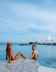 Wall Mural - couple man and woman on a luxury vacation enjoying the infinity pool on the rooftop, Pattaya Thailand. sunny day in Pattaya