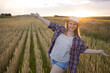 © olga_sova - A beautiful middle-aged farmer woman in a straw hat and a plaid shirt stands in a field of golden ripening wheat during the daytime in the sunlight
