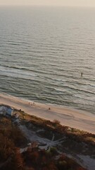 Wall Mural - Bird's-eye view, a group of people stand on a sandy beach washed by foamy waves