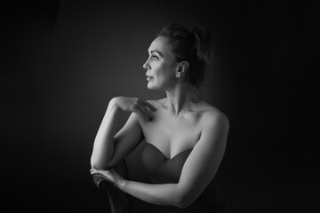 Wall Mural - Portrait of a sensual fifty year old woman on grey studio background. Monochrome shot.