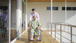 © tampatra - Old elderly disabled Asian patient or pensioner and a doctor using wheelchair to practice to walk in nursing home in hospital. Senior people lifestyle activity recreation. Health care physical therapy