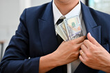 Fototapeta  - Close-up, A businessman putting a wad of US dollar bills into his suit pocket.