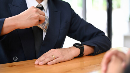 Wall Mural - A businessman putting a wad of US dollar bills into his suit pocket. cropped image