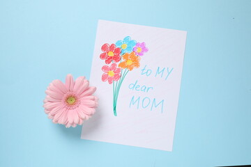 Wall Mural - Handmade greeting card for Mother's day and flower on light blue background, flat lay