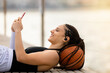 © Valoa Studio - Athletic young woman smiling happy wearing wireless smartphone earphones lying on basketball