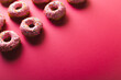 Leinwandbild Motiv High angle view of copy space by arranged donuts with sprinklers on pink background