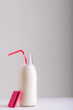 Milk bottle with straw by waffle against white background, copy space