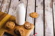 High angle view of milk bottle with cookies on wooden table, copy space