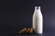Milk bottle with cookies against gray background, copy space