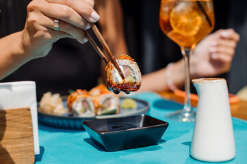 Customer of the restaurant is eating a sushi rolls. Close up