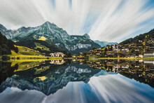 Picturesque Landscape Of Calm Lake Reflecting Mountains And Houses
