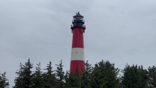 Red And White Lighthouse Behind The Trees In A Soft Rainy Day