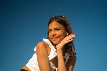 Cheerful adorable child girl sitting and looking at the camera while relaxing