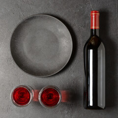 Red wine in a bottle. Black concrete background. Flat lay. Copy space.