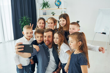 Making a selfie by phone. Group of children students in class at school with teacher