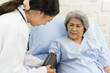 © amorn - Nurse and elderly patient woman. Nurse preparing blood pressure gauge with arm elderly woman patient at the hospital