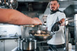 © standret - Pouring ingredients. Professional chef preparing food in the kitchen