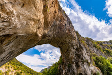 The “Pont D’Arc“ In Vallon-Pont-d'Arc, France Is On Of The Biggest Natural Bridge Or Rock Arches. Spanning Over Ardèche River In Provence It Is A Major Tourist Attraction An Sight. Kayaks Can Pass It.