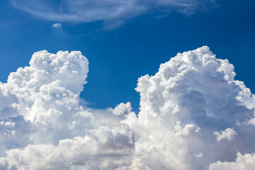 closeup of billowy cumulus clouds. wispy clouds, deep blue sky in background.