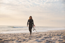 Female Extreme Sports Kite Surfer Prepping Kite On Beach At Sunset