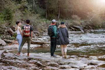 Back view on two couples at rocky fast mountains river standing hand in hand and enjoying view.