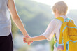 © Maria Sbytova - Little schoolboy with his mother goes to school after summer holiday. Parent accompanies or meets the child. Education for children. Kids back to school concept.
