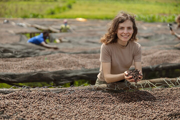 smiling lady holding dried coffee beans in hands at farm in africa region with workers on the backgr