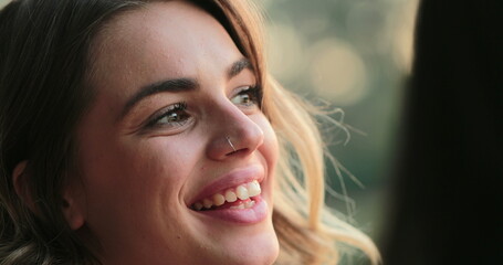 Candid close-up of young woman speaking to friends laughing and smiling. Girl in conversation outdoors