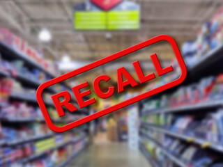 Blurry interior of a grocery store aisle behind large red Recall text