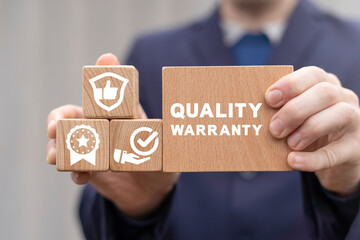 Wall Mural - Quality warranty concept. Businessman holding wooden blocks with quality warranty concept. Advertising product and service quality commitment.
