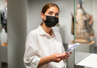 Wall Mural - Young woman wearing face mask observing artworks in museum