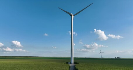 Wall Mural - Low angle aerial of Wind Turbine tower on green corn field with blue sky. Renewable energy sources. Late afternoon light