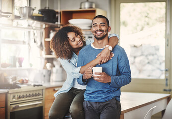 Poster - Happy, hugging and smiling young in love couple bonding in a kitchen at home. Romantic life partners enjoying the morning together feeling relaxed and loving. Portrait of a people embracing romance