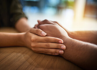 Romantic, caring and in love couple holding hands, wife expressing sympathy and showing support. Female apologizing, comforting or calming upset male on the table at home.