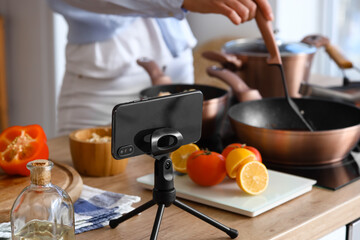 Stand with mobile phone on table in kitchen, closeup