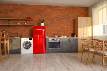 Interior of stylish kitchen with washing machine, fridge and counters