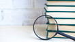© SEA_Ekaterina - Stack of books and magnifying glass
