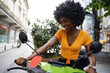 Portrait of young african american woman riding green motorbike in the city