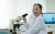 © wichayada - Research Laboratory Portrait of a Professor female scientist using a microscope smiling charmingly on camera Advanced scientific laboratory for medicine biotechnology microbiological development