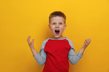 Angry Little Boy Screaming On Yellow Background. Aggressive Behavior