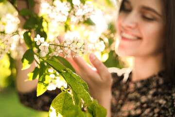 Wall Mural - Beautiful young woman near blossoming tree in park, focus on flowers