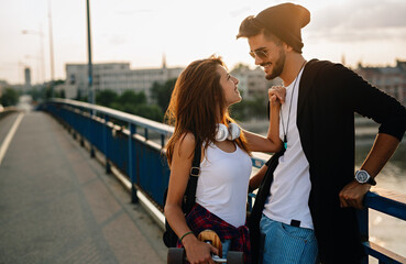 Wall Mural - Portrait of happy couple having fun while driving a long board in city. People skateboard concept