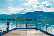 Old Wooden Jetty On The Promenade Of Lovere, Lake Iseo, Italy, With Turquoise Waters. Italian Alps On The Background, With Blue Sky And White Clouds.