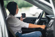 © Ольга Рязанцева - young beautiful brunette woman driver sits in her car with a glass of coffee and starts the car for traffic