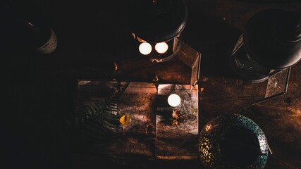 Sticker - View of retro metal lanterns, aromatic candles, green leaf and map on dark wooden table at night